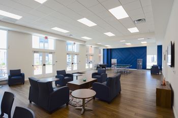 a large room with blue chairs and tables and windows
